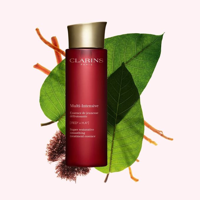 粉紅色背景中的Clarins極緻活齡修護精華水宣傳照，旁邊有紅叉珊藻、哈倫加那葉子和人蔘根。