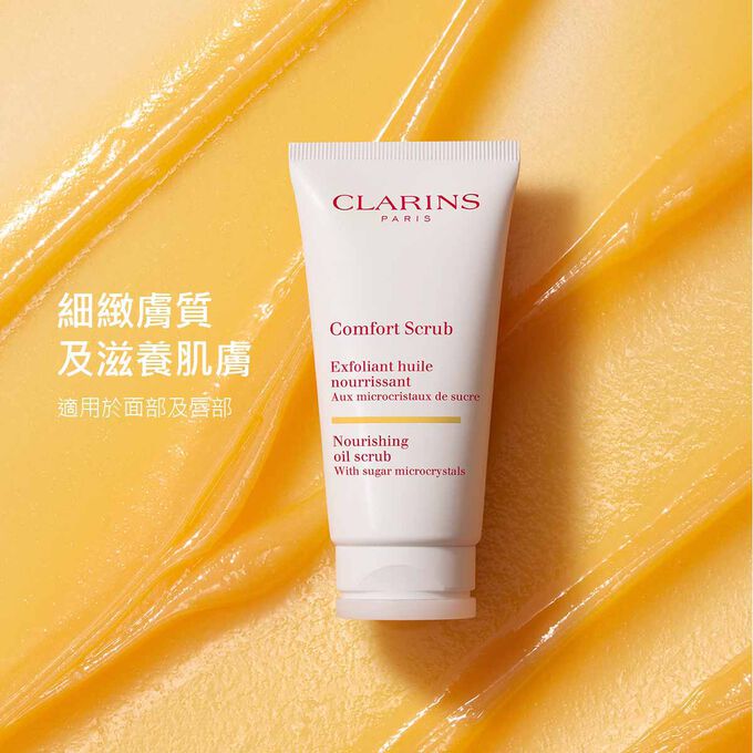 橙色質地背景中適用於面部及唇部的Clarins舒緩磨砂膏，強調產品細緻膚質與滋養肌膚的功效。